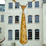 Hauswand, auf der eine grosse gelbe Krawatte gemalt ist