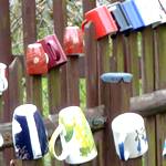 Holzzaun, auf dessen Pfosten bunte Becher stecken