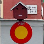 Lustiges Schild mit Gesicht ueber dem Verkehrsschild